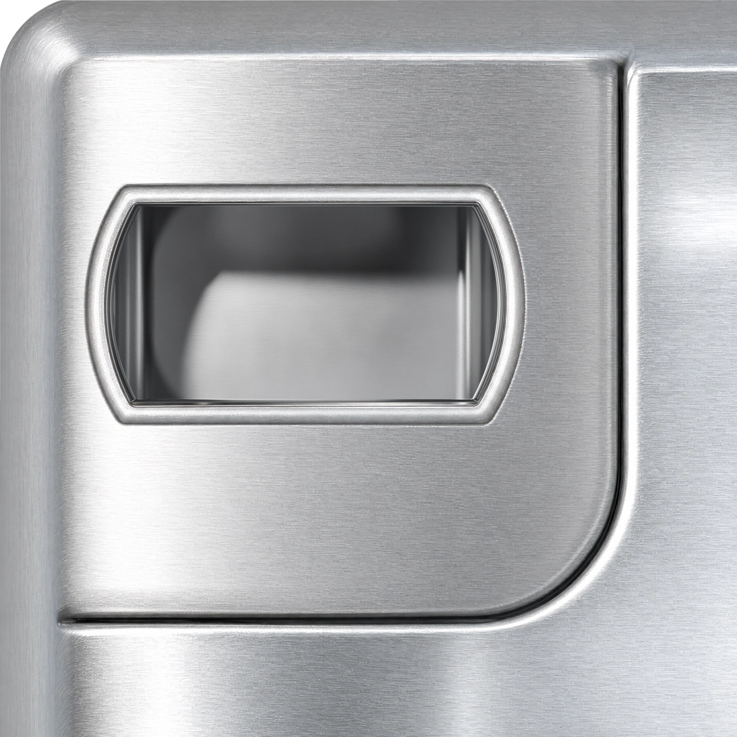 Top face of a stainless steel corner casting, looking down through its oblong opening into the hollow chamber, where light falls across the steel floor beyond the shadow of the rim and more enters through the side and end openings